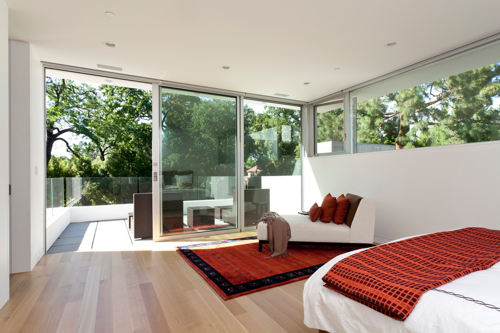 This is an example of a large modern master bedroom in San Francisco with white walls, light hardwood floors and no fireplace.