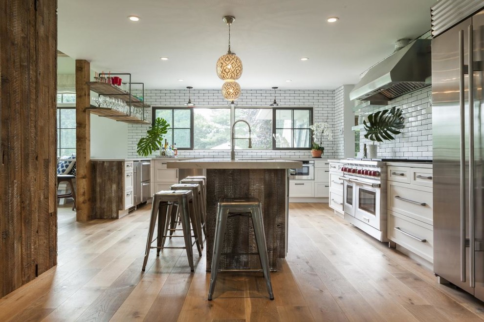Large contemporary single-wall eat-in kitchen in New York with with island, a drop-in sink, beaded inset cabinets, white cabinets, stainless steel appliances and medium hardwood floors.