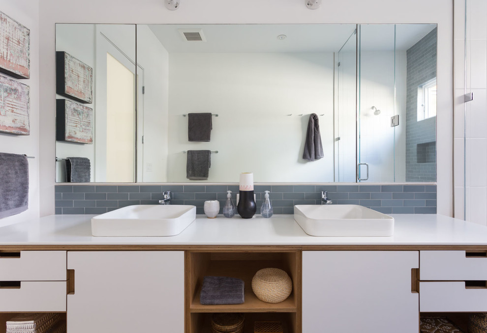 Large midcentury master bathroom in San Francisco with furniture-like cabinets, white cabinets, a freestanding tub, an alcove shower, a two-piece toilet, blue tile, subway tile, white walls, medium hardwood floors, a vessel sink, solid surface benchtops, brown floor and a hinged shower door.