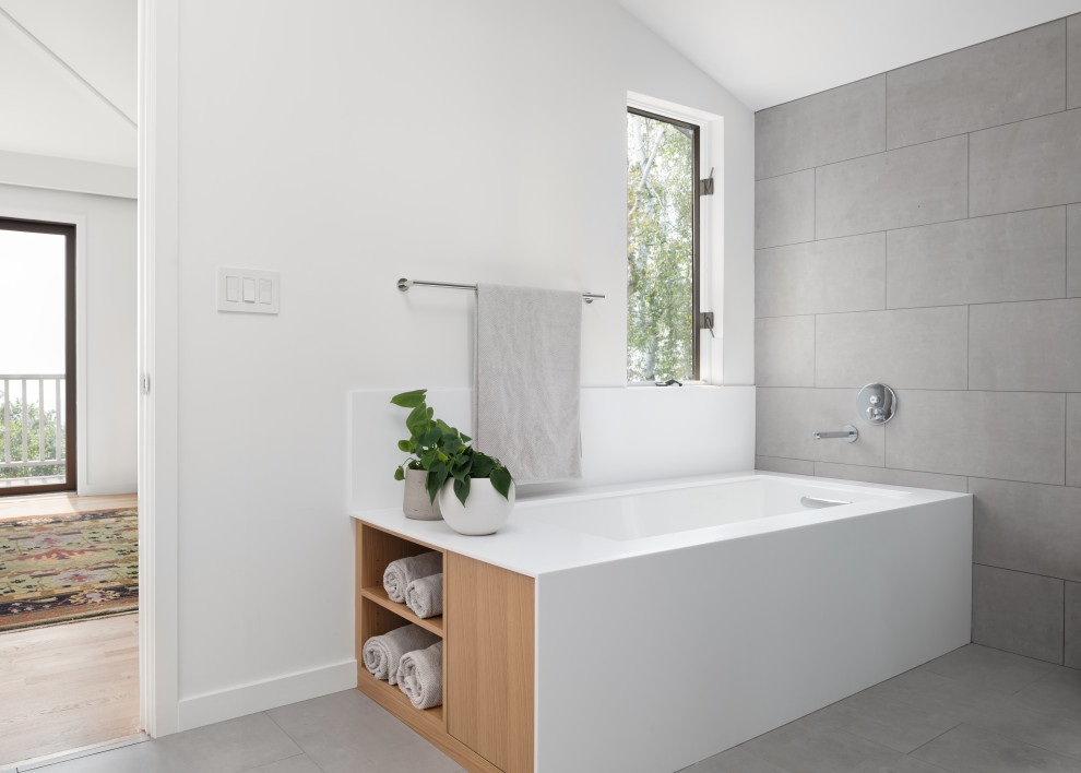 Design ideas for a large modern ensuite bathroom in San Francisco with flat-panel cabinets, white cabinets, a submerged bath, a built-in shower, a wall mounted toilet, grey tiles, porcelain tiles, white walls, porcelain flooring, a submerged sink, engineered stone worktops, grey floors, white worktops, double sinks, a floating vanity unit and a vaulted ceiling.