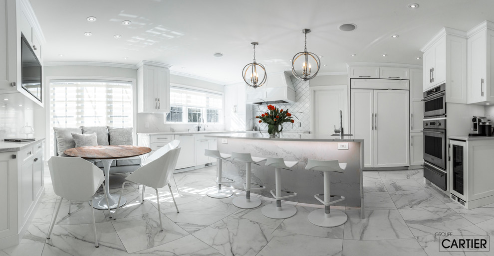 Example of a huge transitional l-shaped marble floor eat-in kitchen design in Montreal with an undermount sink, shaker cabinets, white cabinets, quartzite countertops, gray backsplash, glass tile backsplash, paneled appliances and an island