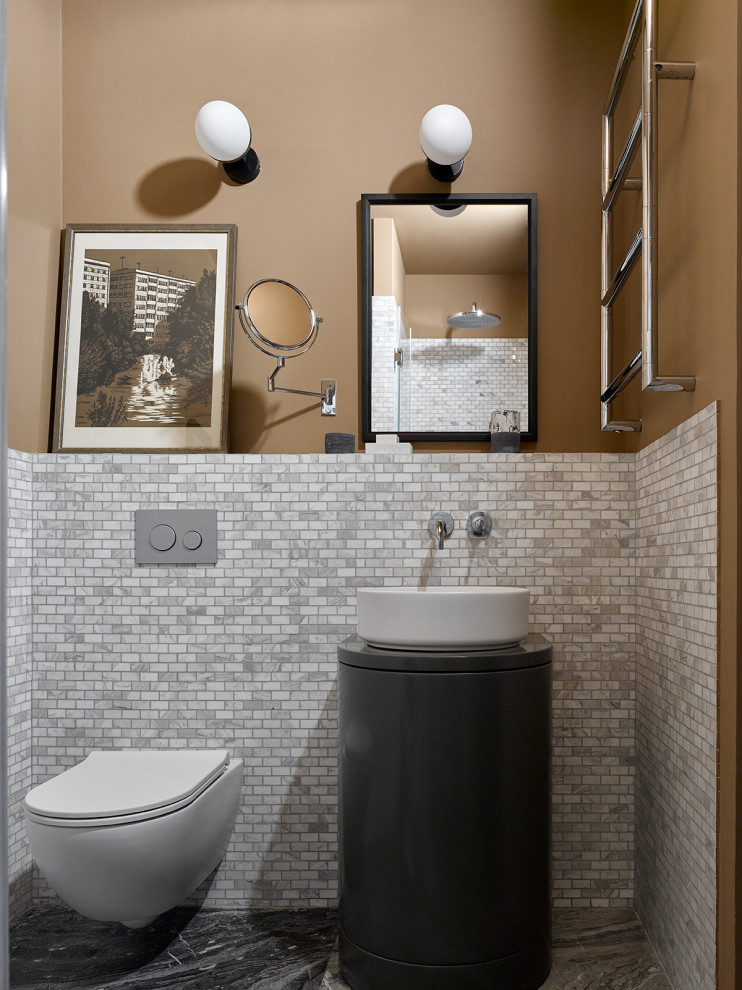 Photo of a contemporary powder room in Moscow with flat-panel cabinets, black cabinets, a wall-mount toilet, gray tile, beige walls, a vessel sink, grey floor, black benchtops and a freestanding vanity.