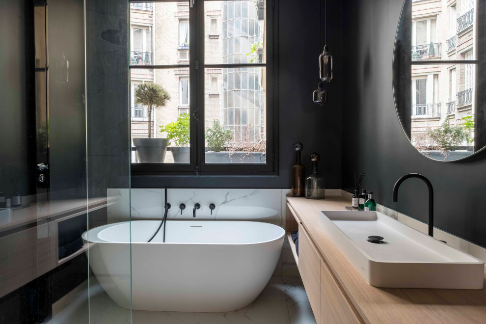 Large contemporary master bathroom in Paris with flat-panel cabinets, light wood cabinets, a freestanding tub, a corner shower, black walls, ceramic floors, a console sink, wood benchtops, grey floor, an open shower and brown benchtops.