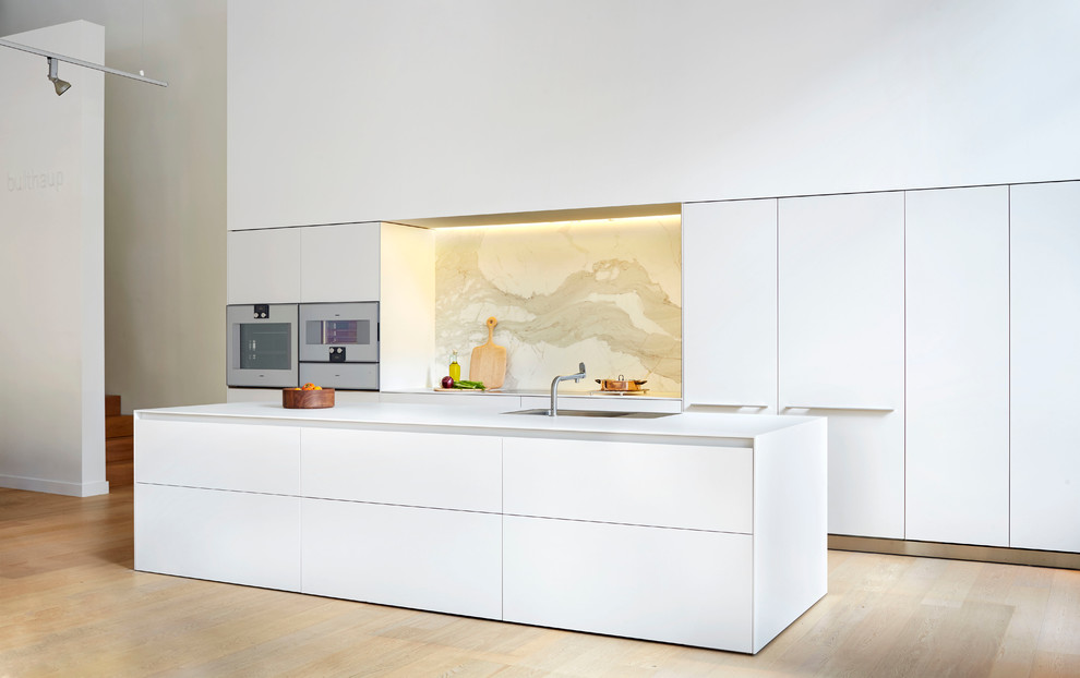 This is an example of a large modern eat-in kitchen in Vancouver with an integrated sink, flat-panel cabinets, white cabinets, laminate benchtops, stone slab splashback, with island and panelled appliances.