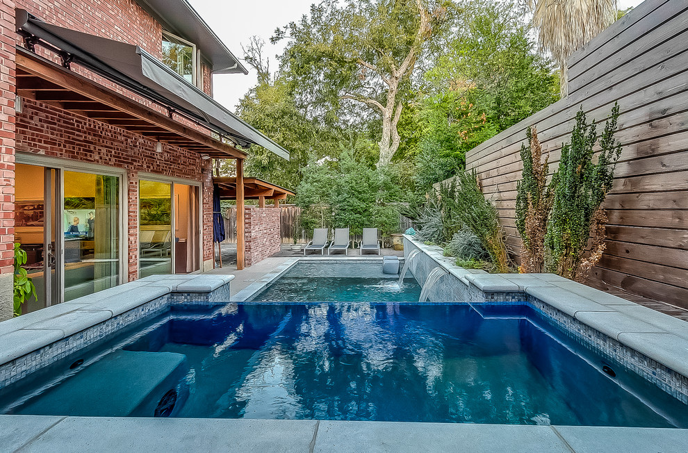 Photo of a mid-sized transitional backyard rectangular infinity pool in Dallas with a hot tub and concrete slab.
