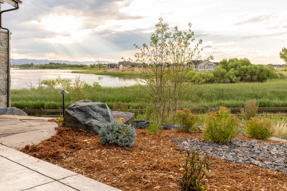 Photo of an expansive arts and crafts backyard full sun garden in Denver with with rock feature and mulch.