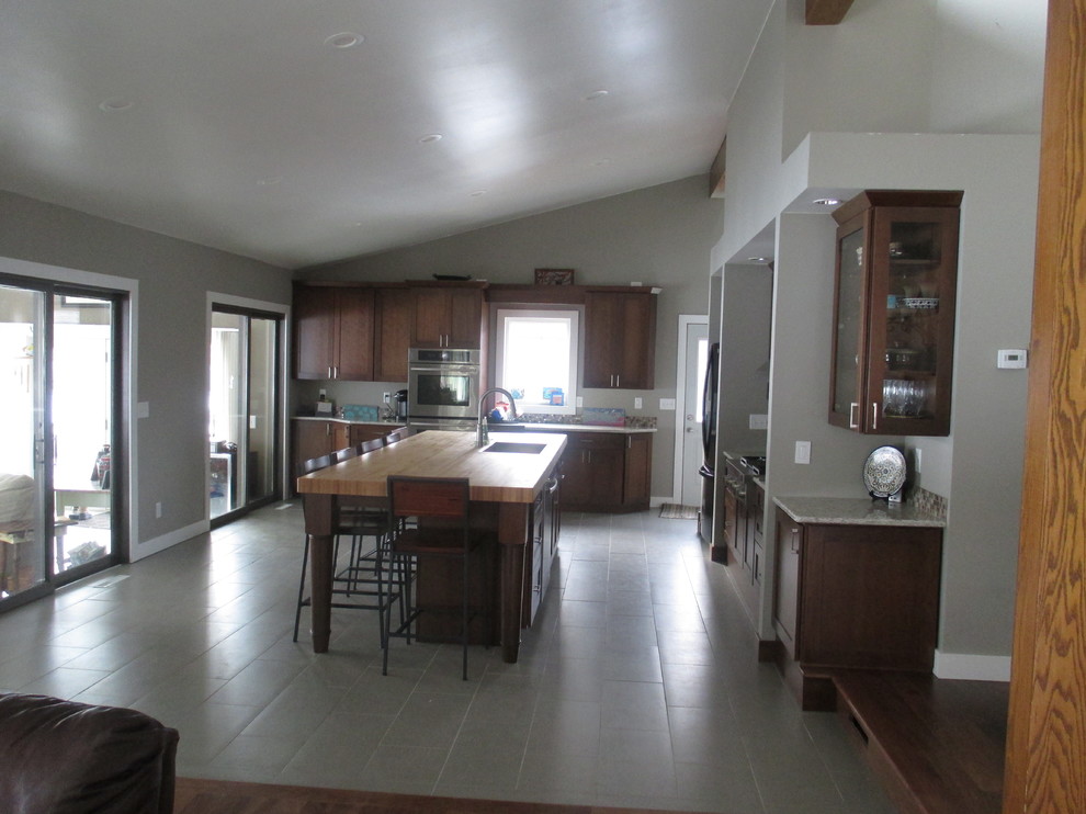 Example of a transitional galley ceramic tile eat-in kitchen design with a drop-in sink, shaker cabinets, dark wood cabinets, quartz countertops, multicolored backsplash, glass tile backsplash, stainless steel appliances and an island