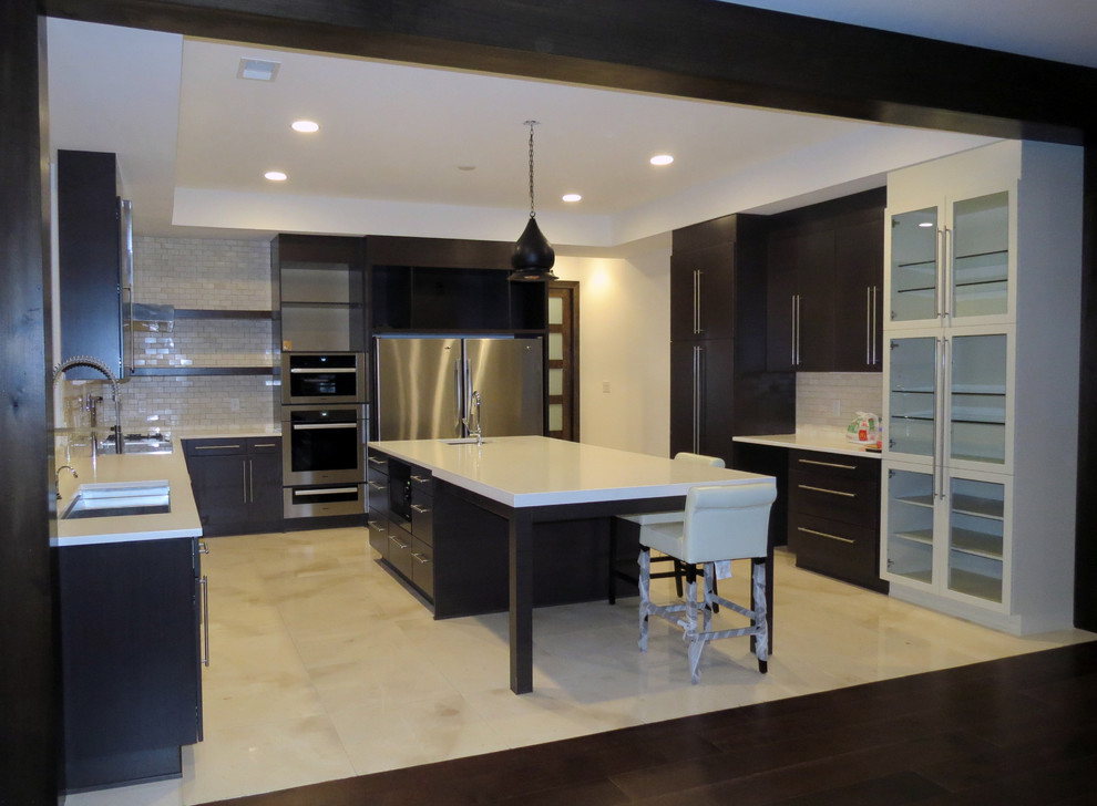 Photo of a large contemporary u-shaped kitchen in Raleigh with a farmhouse sink, glass-front cabinets, dark wood cabinets, granite benchtops, white splashback, subway tile splashback, stainless steel appliances, travertine floors and with island.