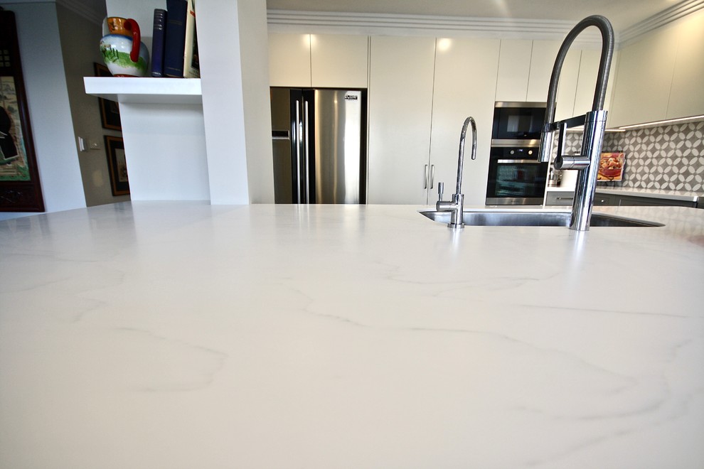 This is an example of a large modern u-shaped eat-in kitchen in Sydney with an undermount sink, shaker cabinets, grey cabinets, quartz benchtops, grey splashback, ceramic splashback, stainless steel appliances, porcelain floors, with island, beige floor and white benchtop.