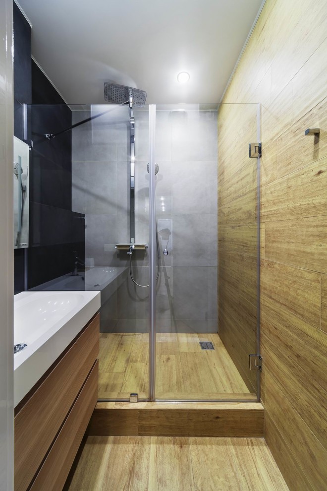 Photo of a contemporary 3/4 bathroom in Yekaterinburg with flat-panel cabinets, an alcove shower, beige tile, gray tile, an integrated sink, beige floor, a hinged shower door and light wood cabinets.