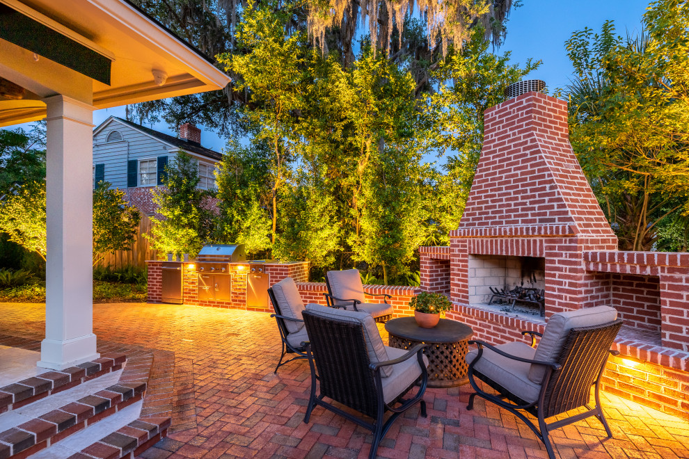 Example of a mid-sized classic backyard brick patio design in Jacksonville with a fireplace and an awning