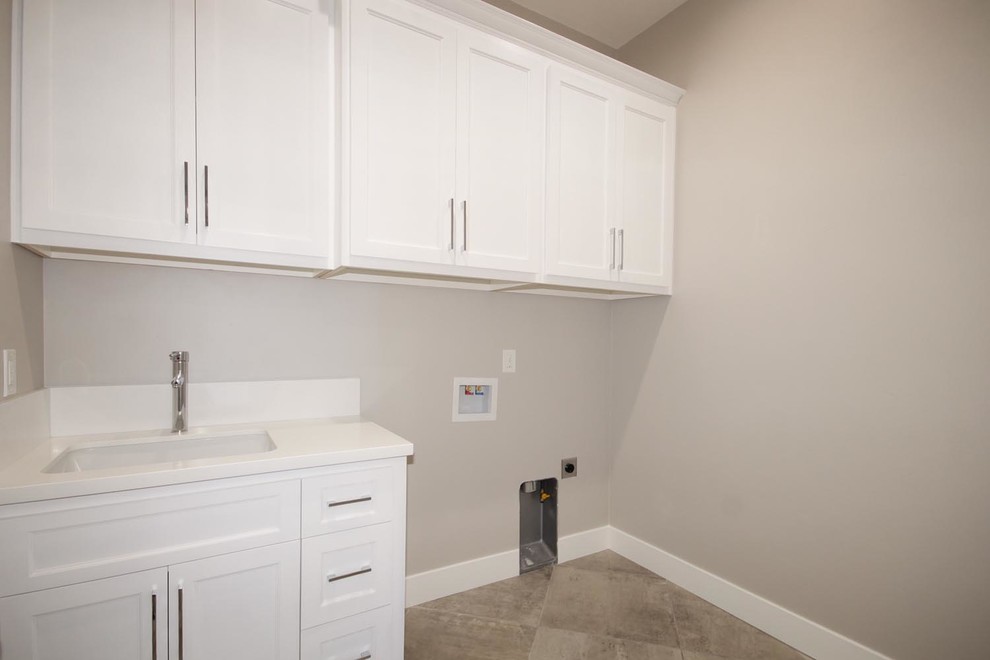 This is an example of a small contemporary single-wall dedicated laundry room in Sacramento with an integrated sink, beaded inset cabinets, white cabinets, limestone benchtops, grey walls, ceramic floors, a side-by-side washer and dryer, beige floor and white benchtop.