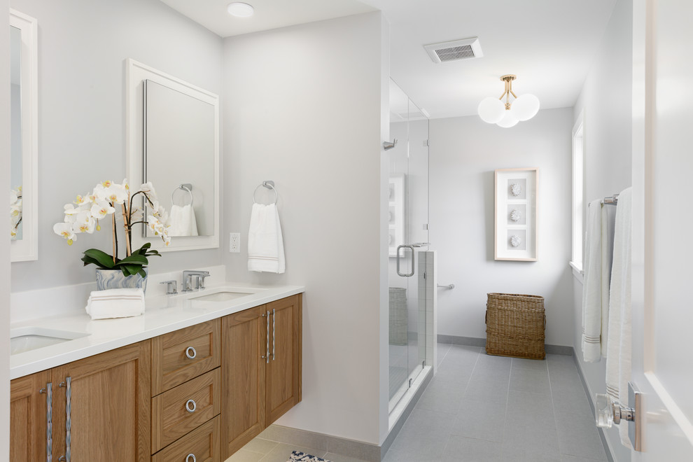 Photo of a mid-sized traditional master bathroom in Minneapolis with white walls, shaker cabinets, medium wood cabinets, an undermount sink, grey floor and white benchtops.
