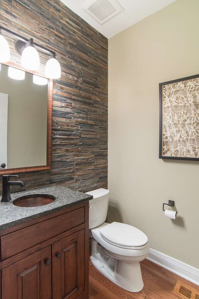 This is an example of a small country bathroom in Chicago with an undermount sink, furniture-like cabinets, medium wood cabinets, granite benchtops, a two-piece toilet, multi-coloured tile, medium hardwood floors and multi-coloured walls.
