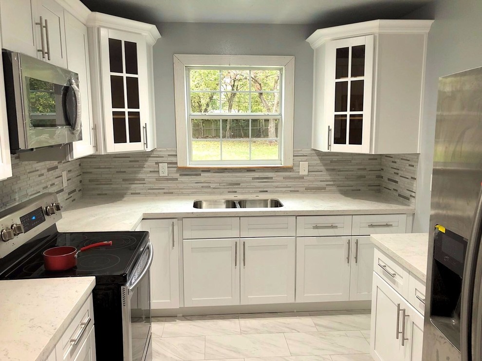 Example of a small transitional u-shaped gray floor enclosed kitchen design in Houston with an undermount sink, shaker cabinets, white cabinets, quartzite countertops, gray backsplash, stone tile backsplash, stainless steel appliances and no island