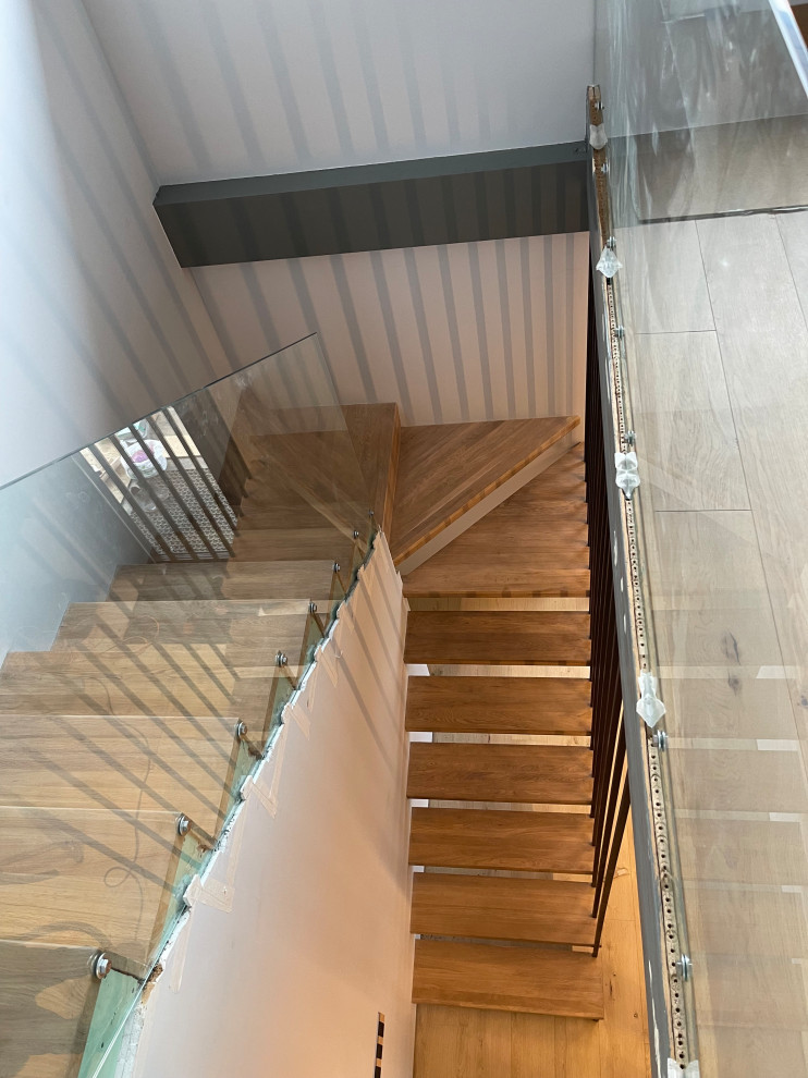 Идея дизайна: угловая лестница среднего размера в стиле лофт с деревянными ступенями, стеклянными перилами и обоями на стенах