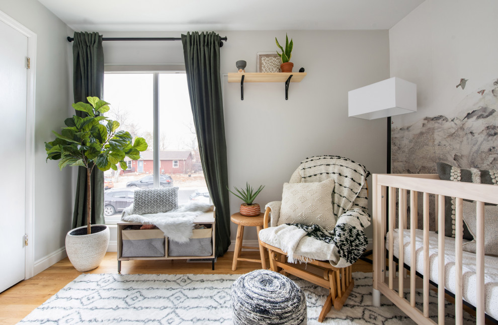 Imagen de habitación de bebé neutra bohemia pequeña con paredes beige, suelo de madera clara y papel pintado