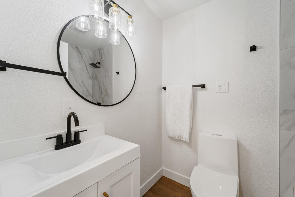 Corner shower - transitional kids' medium tone wood floor, brown floor and single-sink corner shower idea in Seattle with a floating vanity, shaker cabinets, white cabinets, a one-piece toilet, white walls and an integrated sink