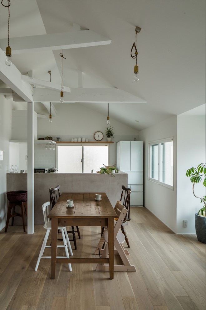 Inspiration for a small traditional single-wall open plan kitchen in Other with an integrated sink, beaded inset cabinets, white cabinets, stainless steel benchtops, white splashback, ceramic splashback, black appliances, light hardwood floors, with island, white floor and grey benchtop.