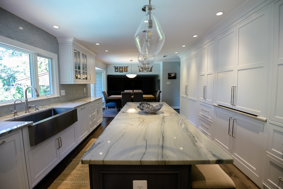 Eat-in kitchen - large transitional u-shaped medium tone wood floor and brown floor eat-in kitchen idea in DC Metro with a farmhouse sink, recessed-panel cabinets, white cabinets, marble countertops, stainless steel appliances, an island, gray backsplash and porcelain backsplash