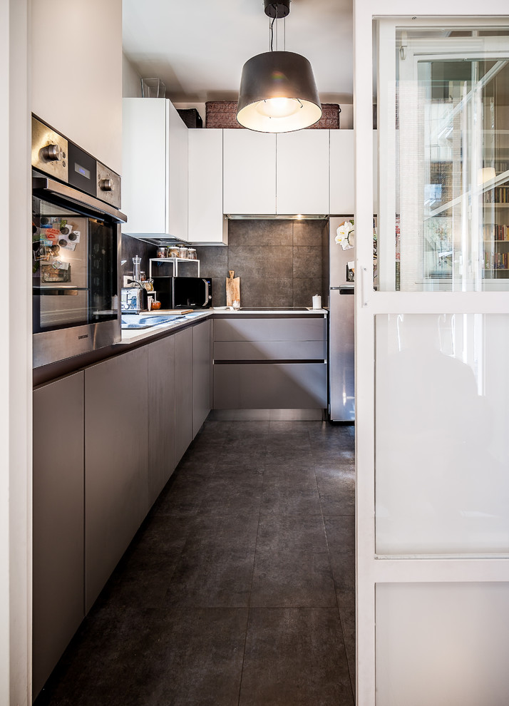 Inspiration for a large contemporary l-shaped separate kitchen in Rome with flat-panel cabinets, grey cabinets, black floor, black splashback, stainless steel appliances and grey benchtop.