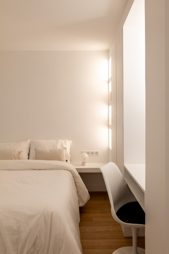 Cette photo montre une chambre beige et blanche tendance de taille moyenne avec un mur blanc, parquet clair, aucune cheminée, un sol marron et dressing.