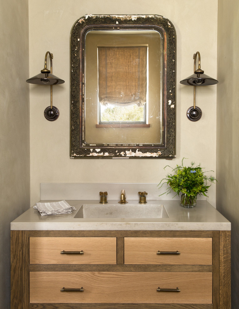 This is an example of a country powder room in San Francisco with an integrated sink, flat-panel cabinets, medium wood cabinets, beige walls and grey benchtops.