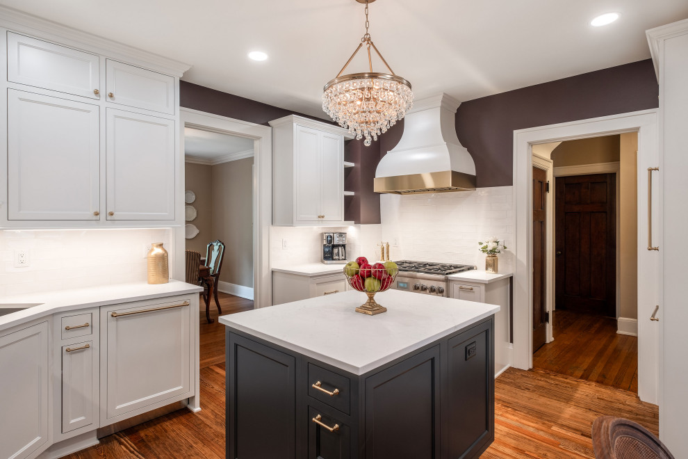 Small u-shaped medium tone wood floor and brown floor enclosed kitchen photo with an undermount sink, recessed-panel cabinets, white cabinets, quartz countertops, white backsplash, porcelain backsplash, stainless steel appliances, an island and white countertops