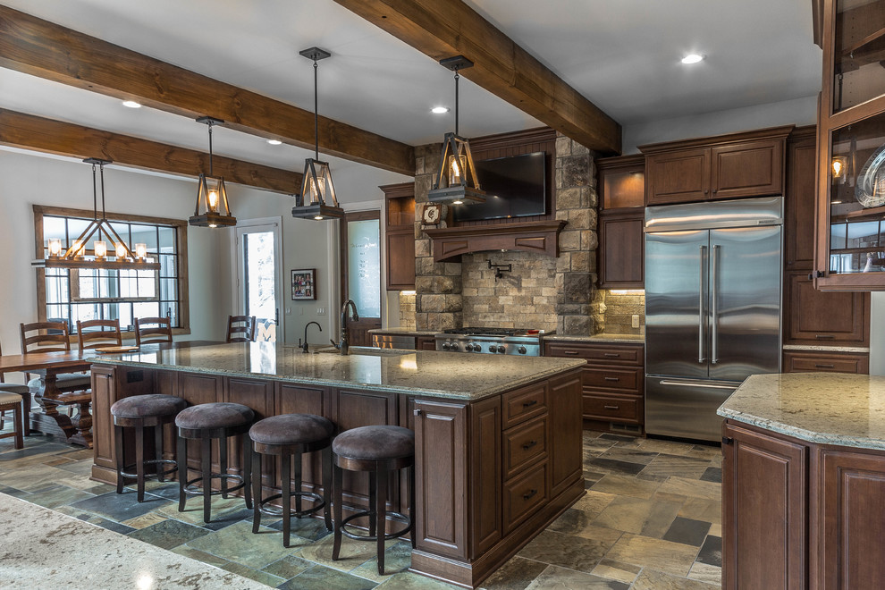 This is an example of an expansive country l-shaped eat-in kitchen in Detroit with an undermount sink, raised-panel cabinets, medium wood cabinets, quartz benchtops, beige splashback, stone tile splashback, stainless steel appliances, slate floors, with island and green floor.
