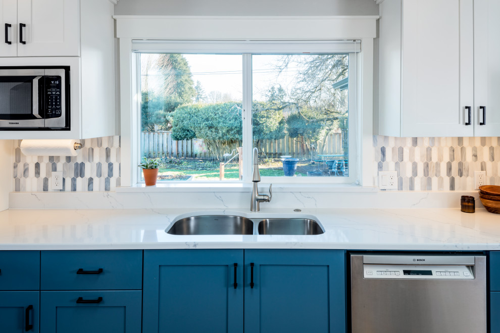 Bild på ett mellanstort vintage vit vitt kök, med en undermonterad diskho, skåp i shakerstil, blå skåp, bänkskiva i kvarts, blått stänkskydd, stänkskydd i mosaik, rostfria vitvaror, ljust trägolv och en halv köksö