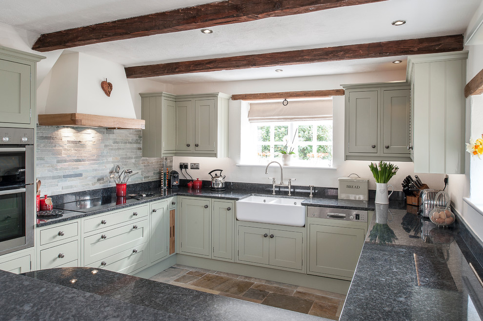 This is an example of a small country u-shaped kitchen in Kent with an undermount sink and limestone floors.