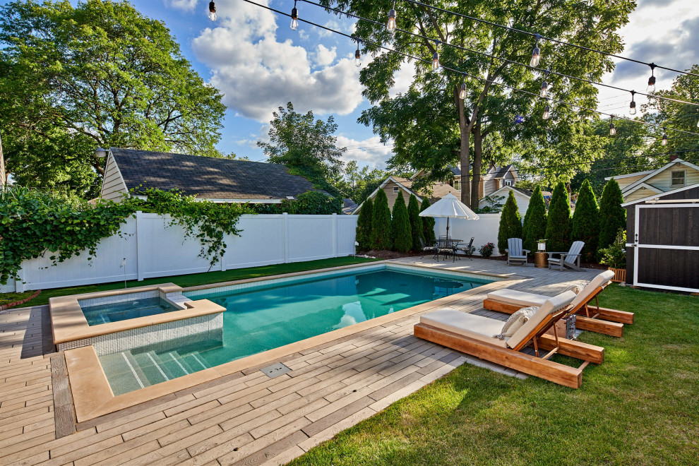 This is an example of a mid-sized contemporary backyard rectangular pool in Detroit with a hot tub and concrete pavers.