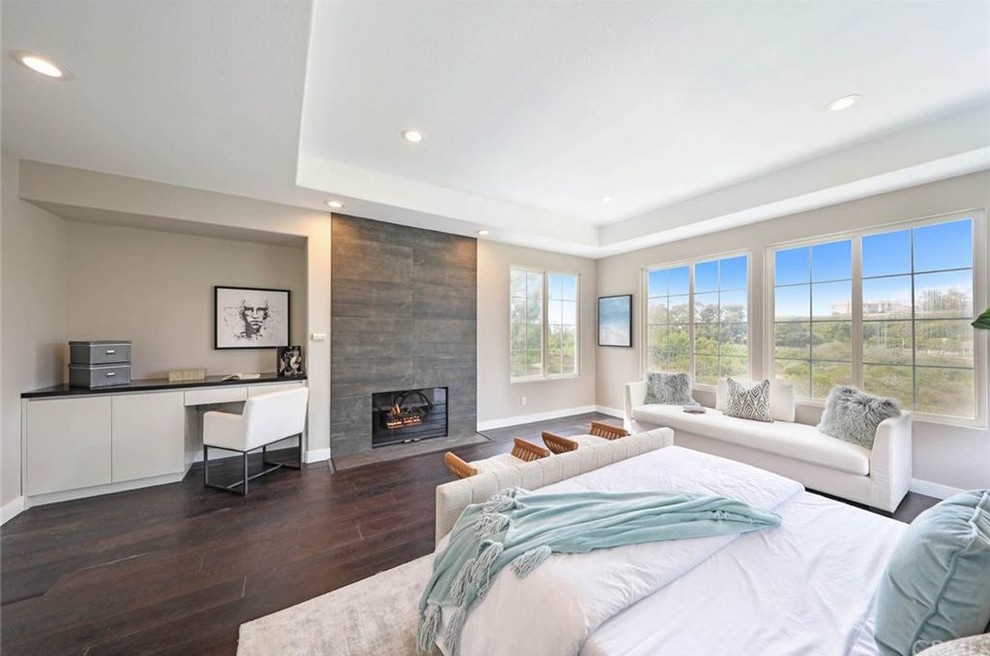 Large contemporary master bedroom in Orange County with dark hardwood floors, a standard fireplace and a tile fireplace surround.