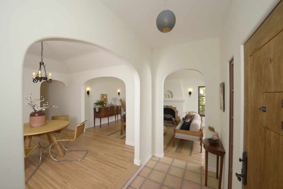 Photo of a mid-sized mediterranean foyer in Los Angeles with a single front door, a light wood front door, white walls and terra-cotta floors.