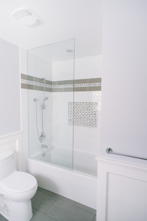 This is an example of a mid-sized transitional kids bathroom in Toronto with a console sink, shaker cabinets, white cabinets, engineered quartz benchtops, an alcove tub, a shower/bathtub combo, gray tile, ceramic tile, grey walls and ceramic floors.