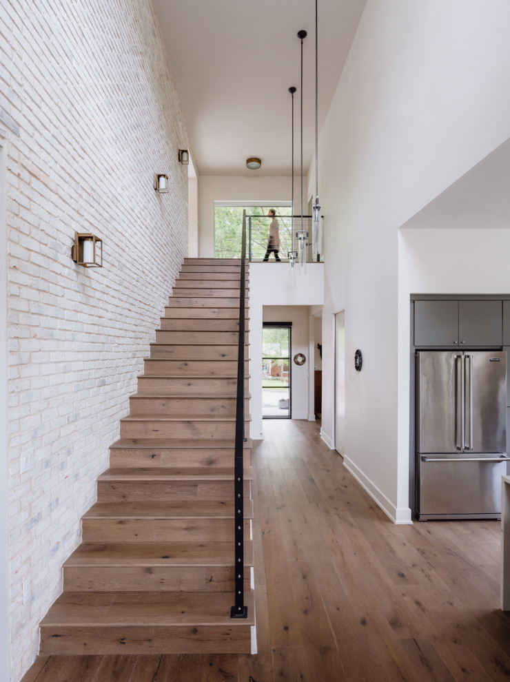 Imagen de escalera recta actual pequeña con escalones de madera, contrahuellas de madera, barandilla de metal y ladrillo