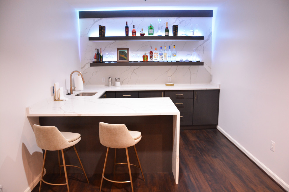 Design ideas for a mid-sized contemporary u-shaped seated home bar in DC Metro with an undermount sink, flat-panel cabinets, dark wood cabinets, quartz benchtops, white splashback, engineered quartz splashback, dark hardwood floors, brown floor and white benchtop.