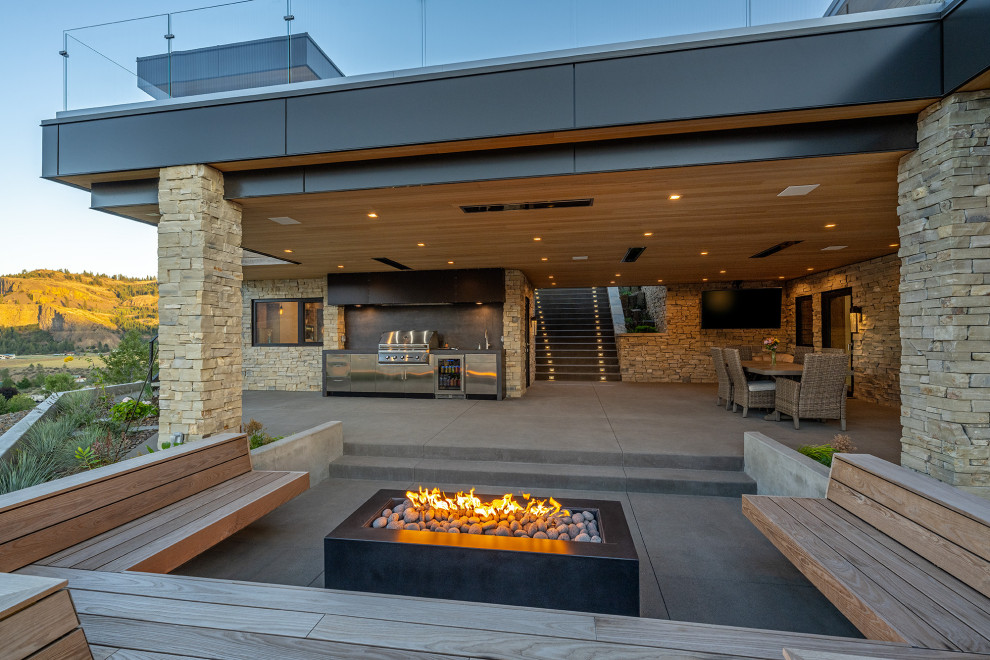 This is an example of a mid-sized contemporary backyard patio in Seattle with a fire feature, concrete slab and a roof extension.