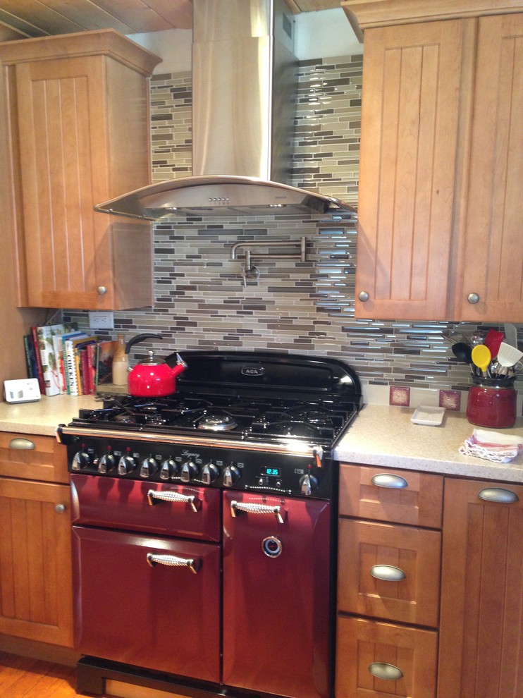 Open concept kitchen - mid-sized rustic l-shaped medium tone wood floor open concept kitchen idea with a farmhouse sink, beaded inset cabinets, light wood cabinets, solid surface countertops, beige backsplash, glass tile backsplash, stainless steel appliances and an island