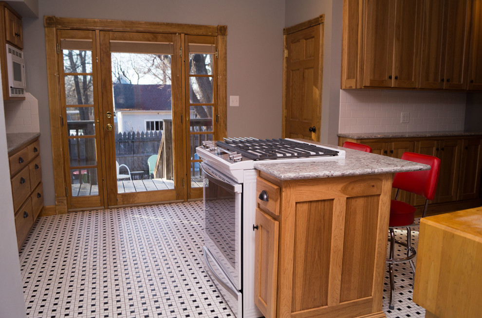Example of a mid-sized ornate ceramic tile enclosed kitchen design with an undermount sink, shaker cabinets, light wood cabinets, granite countertops, white backsplash, ceramic backsplash, white appliances and an island