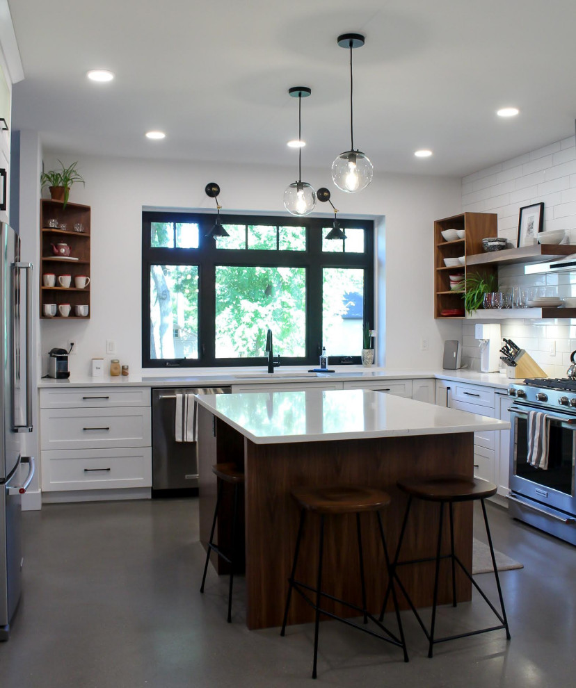 Mid-sized modern u-shaped eat-in kitchen in Other with a double-bowl sink, shaker cabinets, white cabinets, quartz benchtops, white splashback, subway tile splashback, stainless steel appliances, concrete floors, with island, grey floor and white benchtop.