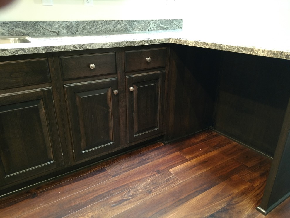 Example of a mid-sized transitional u-shaped laminate floor and multicolored floor kitchen design with a drop-in sink, raised-panel cabinets, dark wood cabinets, laminate countertops, multicolored backsplash, black appliances, a peninsula and multicolored countertops