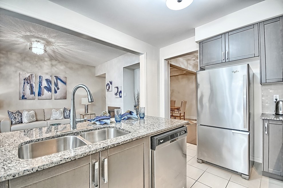 Example of a mid-sized transitional l-shaped ceramic tile and beige floor open concept kitchen design in Toronto with an undermount sink, shaker cabinets, gray cabinets, granite countertops, beige backsplash, mosaic tile backsplash, stainless steel appliances and an island