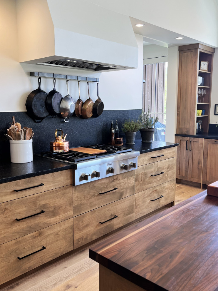 Eat-in kitchen - large transitional galley medium tone wood floor and brown floor eat-in kitchen idea with an undermount sink, flat-panel cabinets, medium tone wood cabinets, quartzite countertops, black backsplash, quartz backsplash, stainless steel appliances, an island and black countertops