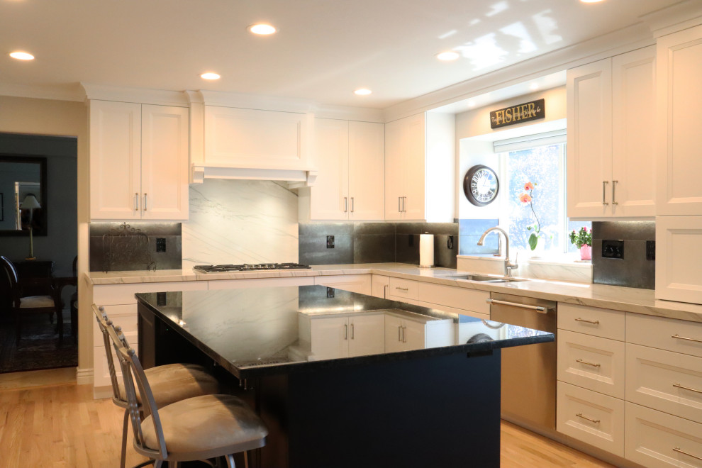 Eat-in kitchen - mid-sized transitional light wood floor eat-in kitchen idea in Salt Lake City with a double-bowl sink, recessed-panel cabinets, white cabinets, white backsplash, marble backsplash, stainless steel appliances, an island and black countertops