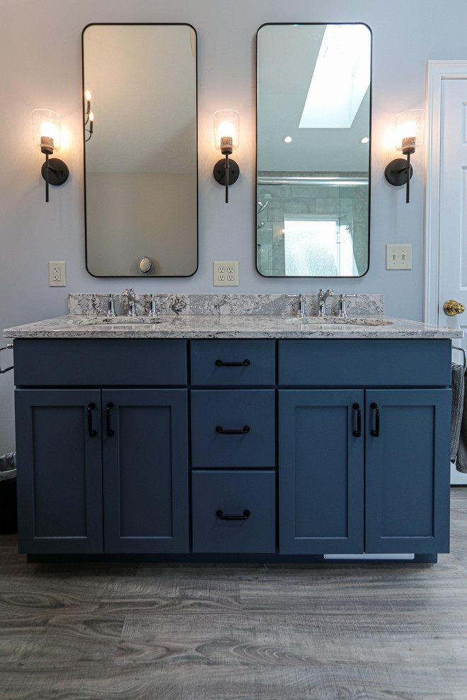 Example of a mid-sized transitional master gray tile and ceramic tile light wood floor, gray floor and double-sink bathroom design in Cleveland with flat-panel cabinets, blue cabinets, a two-piece toilet, blue walls, an undermount sink, quartz countertops, a hinged shower door, gray countertops, a niche and a freestanding vanity