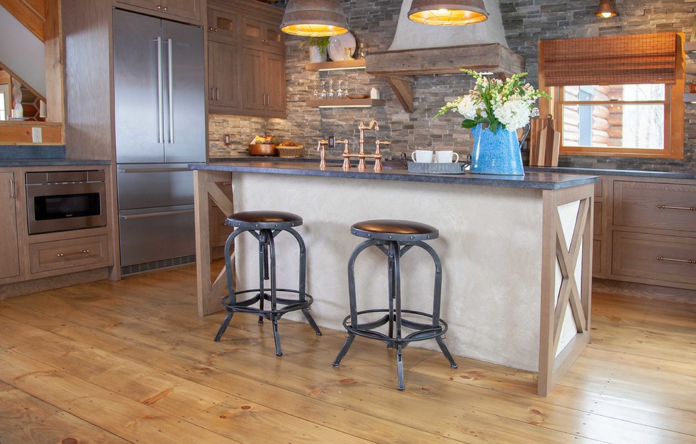 Inspiration for a large country l-shaped eat-in kitchen in Boston with a farmhouse sink, shaker cabinets, medium wood cabinets, soapstone benchtops, grey splashback, stone tile splashback, stainless steel appliances, medium hardwood floors, with island, brown floor and grey benchtop.