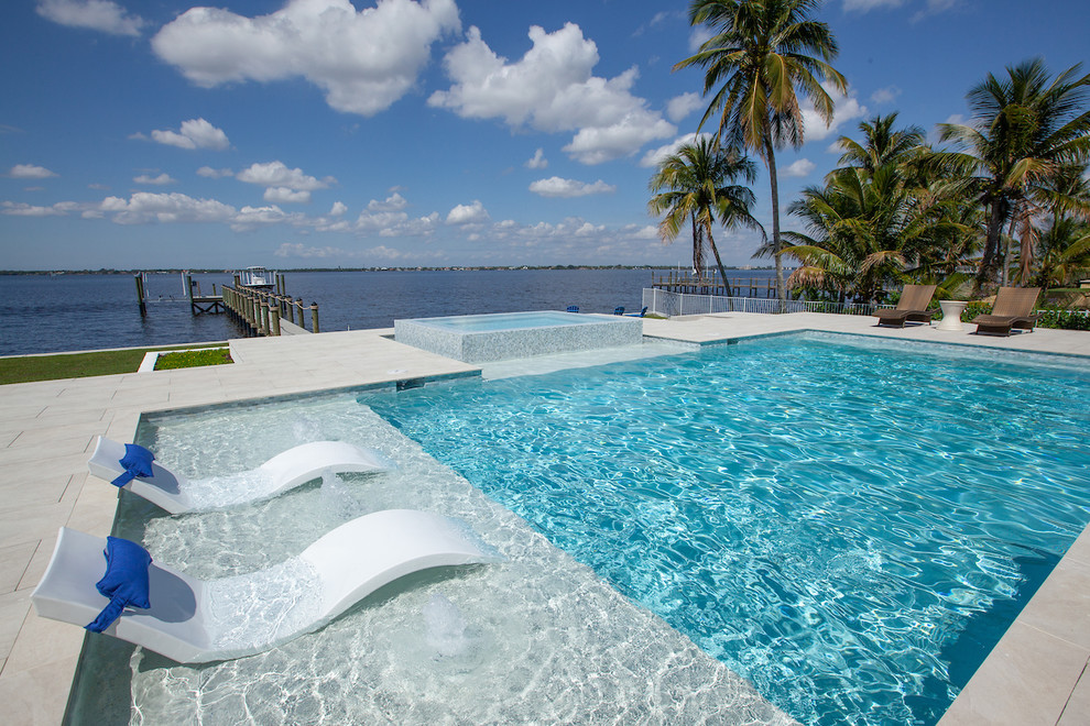 This is an example of a mid-sized modern backyard rectangular infinity pool in Miami with a hot tub and tile.