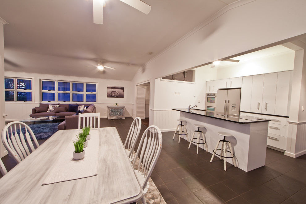 This is an example of a transitional open plan kitchen in Gold Coast - Tweed with a double-bowl sink, white cabinets, granite benchtops, stainless steel appliances and with island.