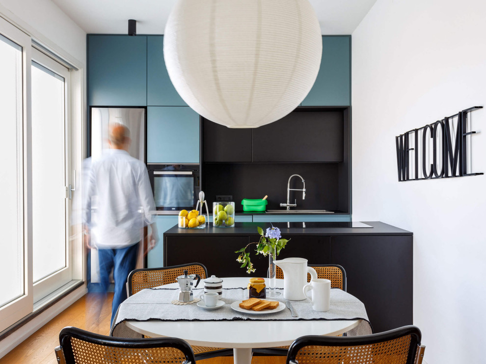 Medium sized contemporary single-wall open plan kitchen in Rome with a built-in sink, beaded cabinets, turquoise cabinets, stainless steel appliances, an island and black worktops.